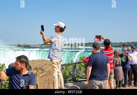 NIAGARA FALLS, Kanada - 25. JULI 2019: Leute, die selfie über Niagara Falls an einem schönen, sonnigen Tag. Kanadische anzeigen. Niagara Falls sind drei Stockfoto