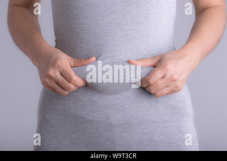 Fette Frau Hand mit übermäßiger Bauch Fett. Healthcare und Frau Diät lifestyle Konzept Bauch zu reduzieren und die Form, gesund Bauch Muskel. Stockfoto