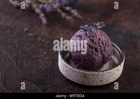 Lavendel Eis in runder grauer Platte auf braunem Hintergrund Stockfoto
