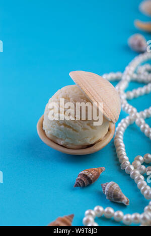 Vanille Eis wie Perle in Muschel auf blauem Hintergrund Deep Sea Pearl Necklace Platz für Text Stockfoto