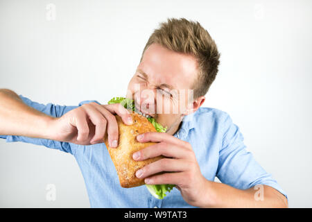 Jungen gutaussehenden Mann beißende frisches Sandwich mit Hunger auf isolierten weißen Hintergrund. Stockfoto