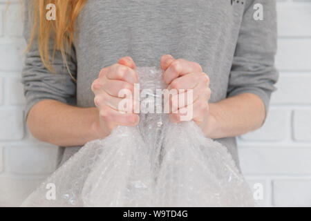 Weibliche Hände knallen die Blasen in Luftpolsterfolie. Selektiver Fokus, Nahaufnahme. Stockfoto