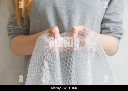 Weibliche Hände knallen die Blasen in Luftpolsterfolie. Selektiver Fokus, Nahaufnahme. Stockfoto