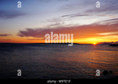 Farbenfroher Sonnenuntergang mit Gelb, Violett und Orange Farbe Ton in windiger Sommertag. Schöne cloudscape mit Anschluss von sinkenden Sonne über den Welligen s Stockfoto