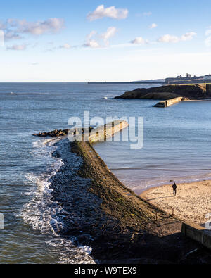 Tynemouth, England, Großbritannien - Februar 4, 2019: Wellen brechen auf dem Stein Hafenmauer von cullercoats Bay auf der Tyneside Nordsee Küste. Stockfoto