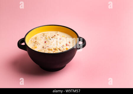 Chowder mit Mais, Garnelen und Speck in schwarz Schüssel auf rosa Hintergrund Stockfoto