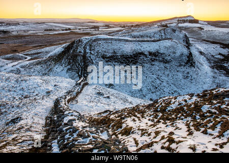 Die Sonne über dem einsamen Maulbeerfeigenbaum auf einmal Gebraut auf dem verschneiten Felsspitzen des Hadrian's Wall in Northumberland. Stockfoto