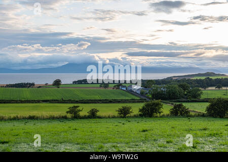 Von West Kilbride in Schottland über typische Ayrshire Ackerland mit Bäumen und Hecken im Abstand gegen eine blau-weiße trübe Skyline w Stockfoto