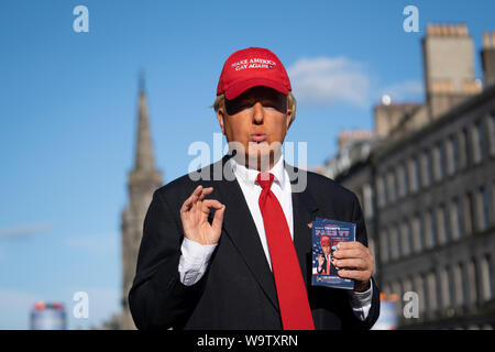 Edinburgh, Schottland, Großbritannien. 15. August 2019. Warme, sonnige Wetter in Edinburgh brachten Tausende von Touristen auf die Royal Mile, die viele Straßenkünstler und Akteure zu genießen die Förderung ihrer zeigt während des Edinburgh Festival Fringe. Donald Trump tritt in Erscheinung Förderung zeigen Trümpfe 'Fake TV. Iain Masterton/Alamy leben Nachrichten Stockfoto