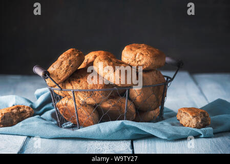 Rustikales Frühstück, frisch gebackenem Roggenbrot Brötchen im Korb auf blauen Handtuch für die Küche. Warme Brötchen im Korb. Gesunde hausgemachten Brötchen. Stockfoto