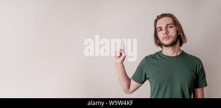 Junger hübscher Kerl oder Mann sein Zeigefinger nach oben an Copyspace leeren Bereich, und isoliert Hintergrund Stockfoto