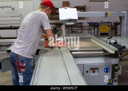 Charkow, Ukraine - Juli 19, 2016: Ein Blick von der Rückseite eines Möbel Workshop Arbeiter arbeiten auf eine Bohrmaschine in einem privaten Möbel Workshop Stockfoto