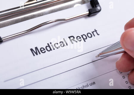 Overhead Ansicht von der menschlichen Hand mit Stift mit medizinischen Bericht über die Zwischenablage auf weißem Hintergrund Stockfoto