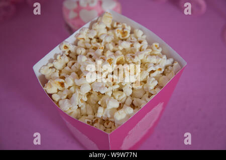 Eine große klassische Feld des Theaters Popcorn auf rosa isoliert. Popcorn verschüttet aus einem gestreiften Box. Drei vintage Stil Boxen von Popcorn in einem Karneval Thema Stockfoto