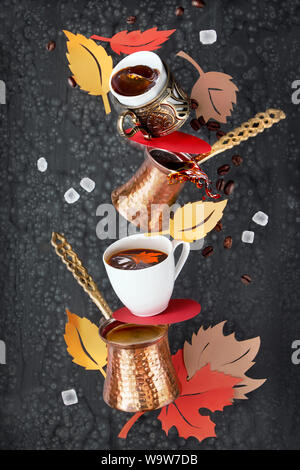 Balancing Pyramide von jezves, türkischer Kaffee Töpfe und Tassen auf dunklem Hintergrund mit Kaffeebohnen und Zucker Stockfoto