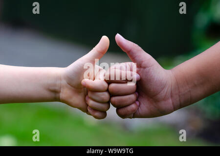 Weißen Jungen und schwarze Mädchen zeigen Daumen hoch oder' wie 'Geste. Konzeptionelle Foto drückt Freundschaft, Frieden, Gleichheit und Vielfalt. Stockfoto