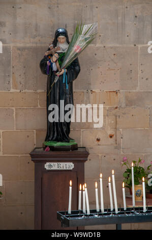 Eine Statue der hl. Rita mit Blumen und Kerzen in der Kirche Saint-Jacques in Dieppe, Frankreich. Stockfoto