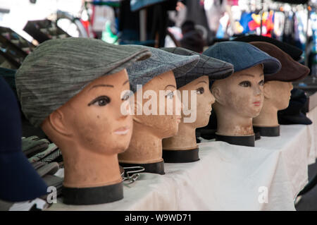 Eine Anzeige von flacher Deckel Hüte auf mannequin Köpfe an einem Stand im Markt im Freien in Dieppe, Frankreich. Stockfoto