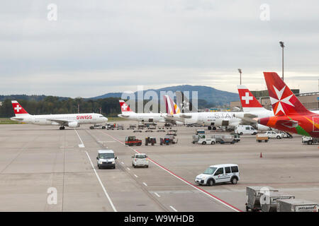 Flugzeuge auftanken und Laden am Flughafen Zürich, Schweiz, der Maltesischen Luft, Swiss Air und Star Alliance Flugzeuge an einem bewölkten winter Eveni Stockfoto