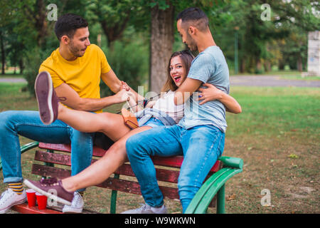 Freunde sitzen auf einer Bank im Park, Witze und Spaß haben Stockfoto