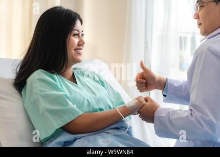 Hand des Menschen Arzt beruhigt seine Patientin mit thump oben im Bett im Krankenhaus. Medizinische Ethik und Vertrauen Konzept. Stockfoto