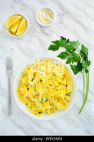Pappardelle Italienische ei Nudeln mit Zitrone und Parmesan auf Marmor Hintergrund in Flach Komposition. Einfache gesunde Ernährung Konzept. Stockfoto