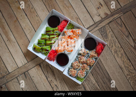 Japanische Küche. Sushi auf einem Baum Karton über Holz- Hintergrund. Essen zum Mitnehmen oder Sushi Konzepts Stockfoto