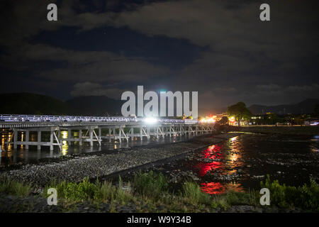 Lichter von der Stadt spiegeln von Wasser neben alten Japanischen Holzbrücke Stockfoto