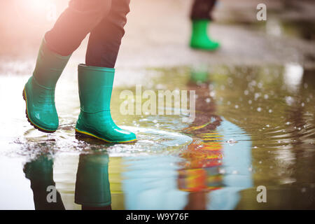 Kind zu Fuß in Gummistiefel in Pfütze auf Regenwetter Stockfoto