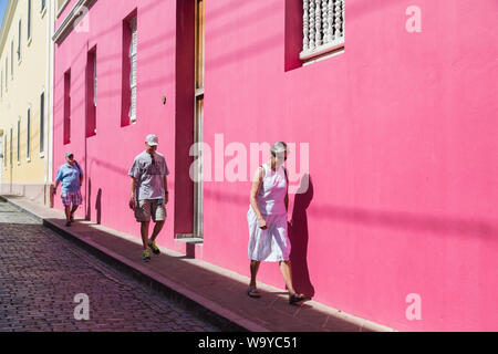 Touristen Spaziergang auf der alten Ziegel Pflaster durch bunte Häuser unter der starken Nachmittag Sonne in der Altstadt von San Juan, San Juan, Puerto Rico. Stockfoto