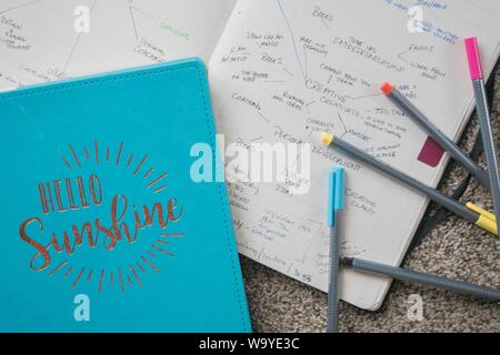 Overhead-Aufnahme eines 'Hello Sunshine'-Lehrbuchs auf einem geöffneten Lehrbuch mit bunten Stiften darauf Stockfoto