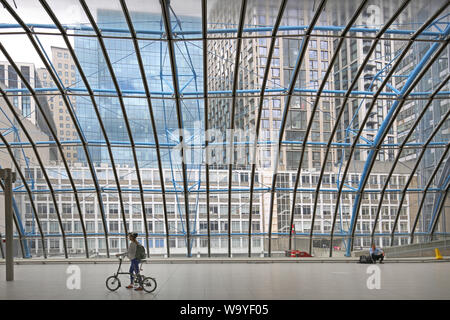 Ein Radfahrer und einzelne Passagier gegen die Fenster in der alten Eurostar Terminal am Londoner Bahnhof Waterloo, wiedereröffnet als Plattformen für Nahverkehrszüge. Stockfoto