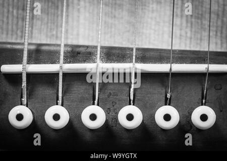 Nahaufnahme Graustufenaufnahme der Brückenstifte der akustischen Gitarre Stockfoto