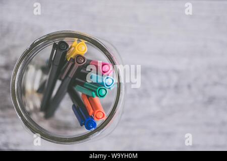 Nahaufnahme von bunten Stiften und Markern in einem Glas Auf grauem Hintergrund Stockfoto