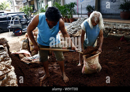 ANTIPOLO CITY, Philippinen - 12. AUGUST 2019: Bauarbeiter sammeln Schmutz oder Boden in einen Sack an einer Baustelle. Stockfoto