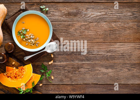 Kürbissuppe. Vegetarische Suppe mit Kürbiskerne in Schale auf Holztisch, Ansicht von oben Stockfoto