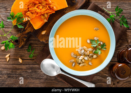 Kürbissuppe. Vegetarische Suppe mit Kürbiskerne in Schale auf Holztisch, Ansicht von oben Stockfoto