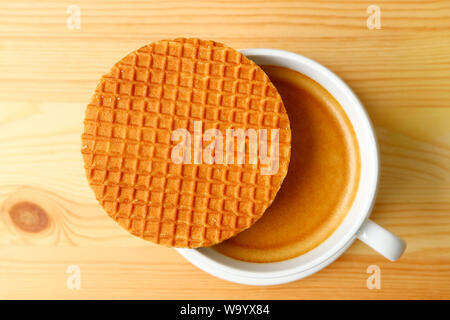 Blick von oben auf eine Stroopwafel platziert Auf heissen Kaffee Tasse serviert auf hölzernen Tisch Stockfoto
