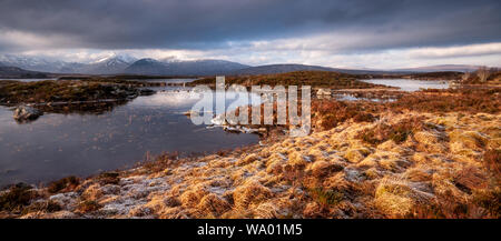 Winter-Eis überzieht man Na h-Achlaise See auf der großen Torfmoor Heide von Rannoch Moor, mit schneebedeckten schwarzen Berge in der Ferne. Stockfoto