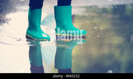 Kind zu Fuß in Gummistiefel in Pfütze auf Regenwetter Stockfoto