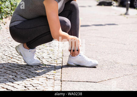 In der Nähe der weiblichen Jogger Leiden Knöchelverletzung auf der Straße Stockfoto