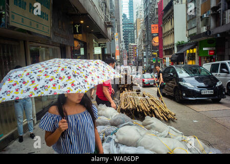 Hongkong, China. 16 Aug, 2019. Ein Arbeitnehmer, der Stapel Bambusrohren auf einer Straße. In Hongkong gab es massive Proteste für mehr als zwei Monate. Die Demonstrationen wurden durch eine Gesetzesvorlage der Regierung ausgelöst - jetzt in der Warteschleife - Verdacht auf Auslieferung von Verbrechern zu China. Credit: Gregor Fischer/dpa/Alamy leben Nachrichten Stockfoto