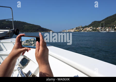 Weibliche Touristen auf dem Schiff nimmt Handy Fotos von der Küste bei Porto Venere; Golf von La Spezia, Ligurien, Italien, Kopie Raum Stockfoto