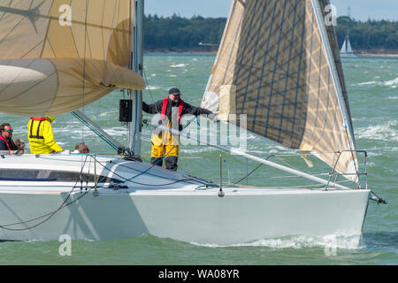 Während der jährlichen cowes Week Regatta auf der Insel Wight, die als Bowman agiert, beugt sich ein Wachmann auf dem Deck und beugt sich auf einer großen Rennyacht. Stockfoto