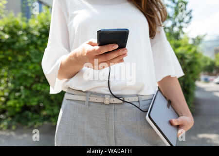 Nahaufnahme von Frau mit Mobiltelefon und externe Batterie Stockfoto
