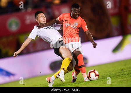 Kenianische Fußballspieler Ayub Masika, rechts, von Peking Renhe passt den Ball gegen einen Spieler von Hebei China Fortune in der 22. Runde während der 2019 chinesischen Fußballverband Super League (CSL) in Peking, China, 14. August 2019. Hebei China Fortune besiegt Peking Renhe 2-1. Stockfoto