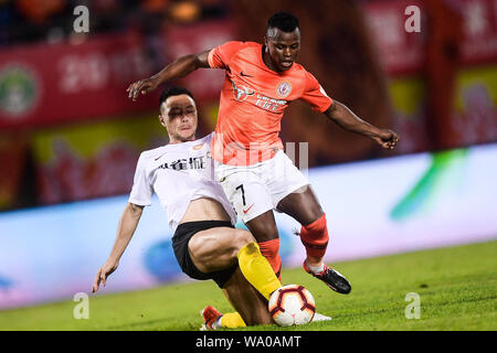 Kenianische Fußballspieler Ayub Masika, rechts, von Peking Renhe passt den Ball gegen einen Spieler von Hebei China Fortune in der 22. Runde während der 2019 chinesischen Fußballverband Super League (CSL) in Peking, China, 14. August 2019. Hebei China Fortune besiegt Peking Renhe 2-1. Stockfoto