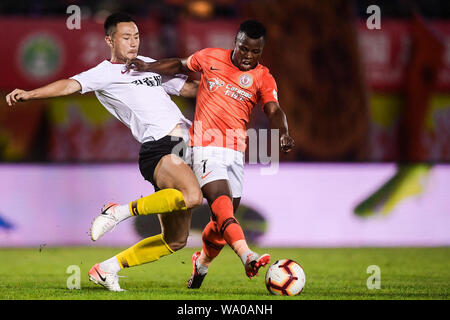 Kenianische Fußballspieler Ayub Masika, rechts, von Peking Renhe passt den Ball gegen einen Spieler von Hebei China Fortune in der 22. Runde während der 2019 chinesischen Fußballverband Super League (CSL) in Peking, China, 14. August 2019. Hebei China Fortune besiegt Peking Renhe 2-1. Stockfoto