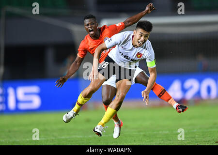 Kenianische Fußballspieler Ayub Masika, links, von Peking Renhe Herausforderungen ein Spieler von Hebei China Fortune in der 22. Runde während der 2019 chinesischen Fußballverband Super League (CSL) in Peking, China, 14. August 2019. Hebei China Fortune besiegt Peking Renhe 2-1. Stockfoto