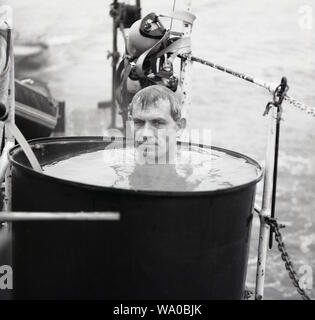 1950, historische, eine shipman in eine Wanne mit Wasser auf dem Deck eines Schiffes gefüllt sitzend, Stockfoto